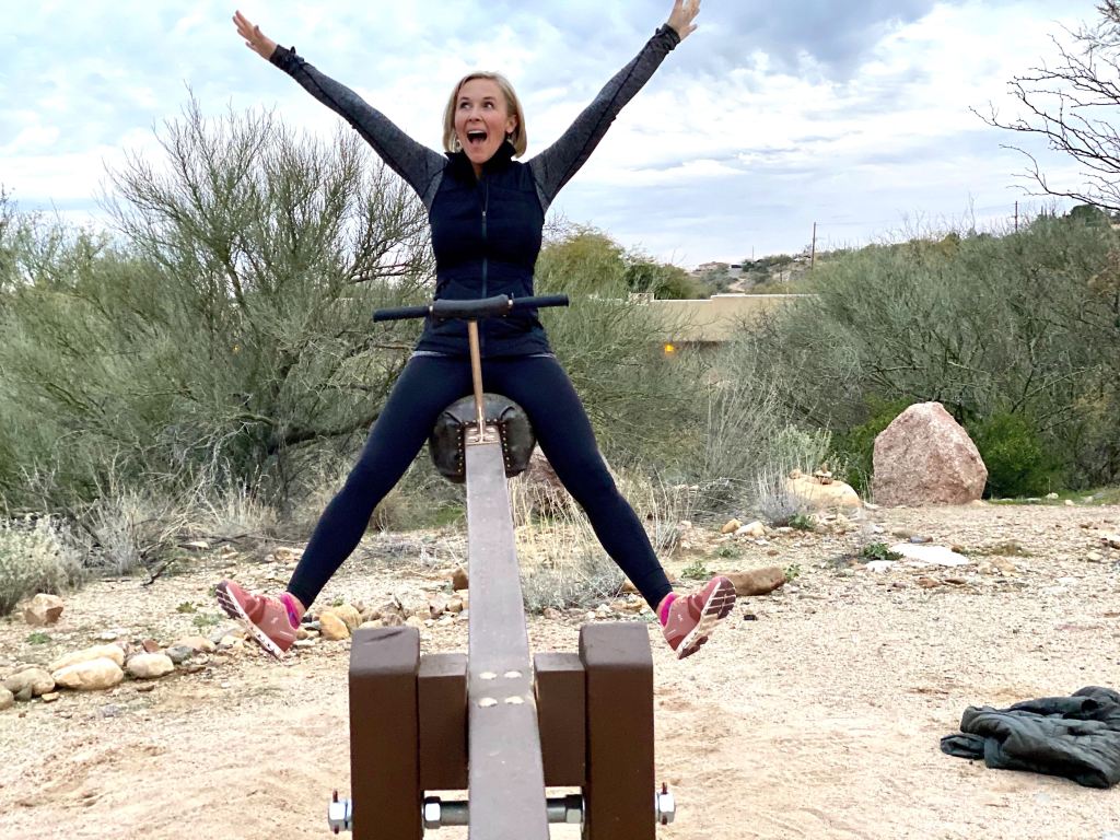 woman with arms up and excited on see-saw 