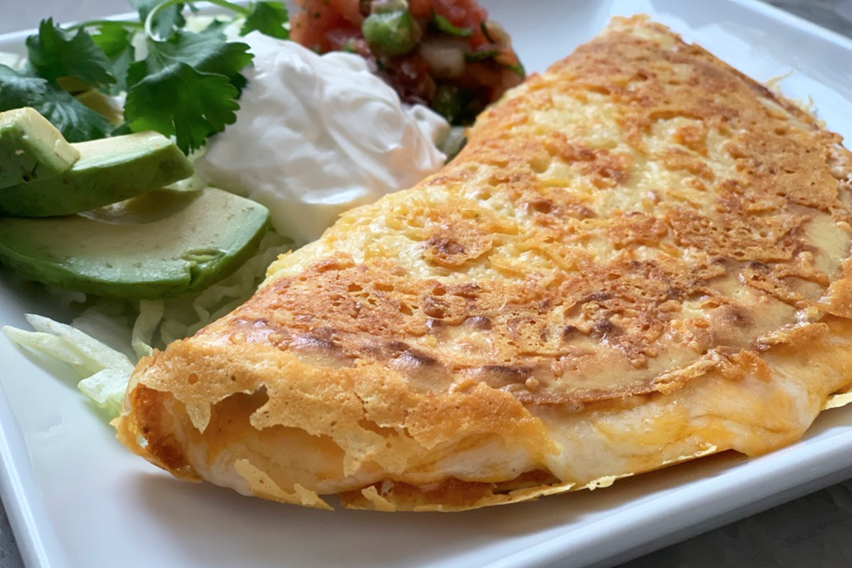 a plate with a keto quesadilla along with avocado sour cream and pico de gallo