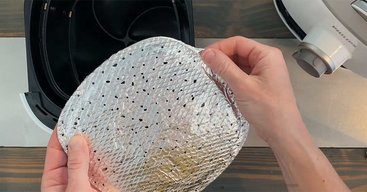 An air fryer grate wrapped with perforated tin foil
