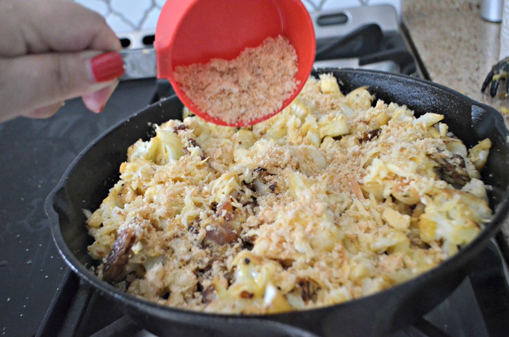 pouring pork rinds onto mac and cheese skillet