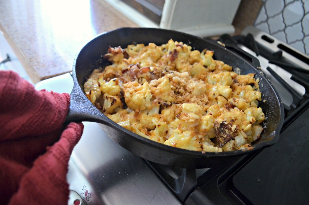 cauliflower mac and cheese on stove in cast iron pan 