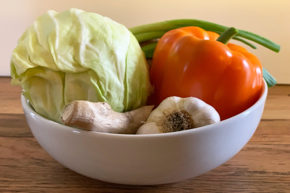 A bow of veggies including cabbage, bell pepper, garlic and ginger