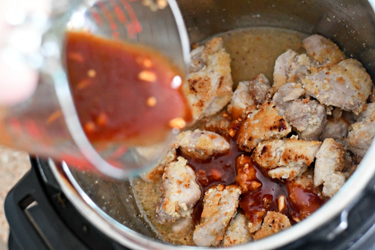 pouring sauce over instant pot chicken before cooking