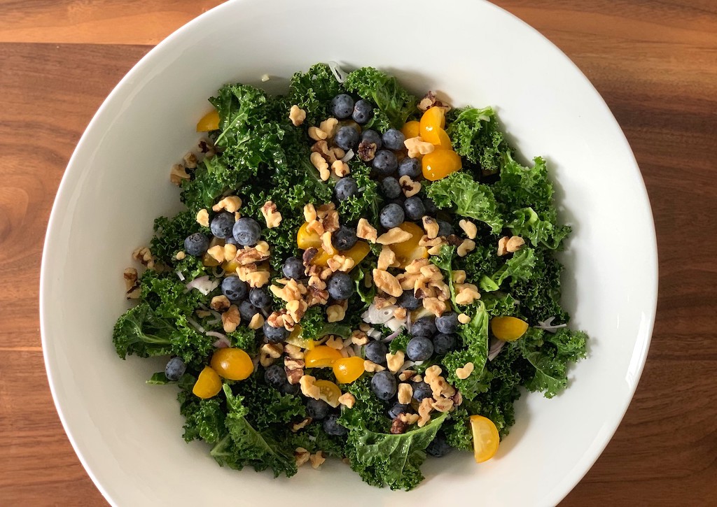 kale salad in bowl with blueberries and nuts 