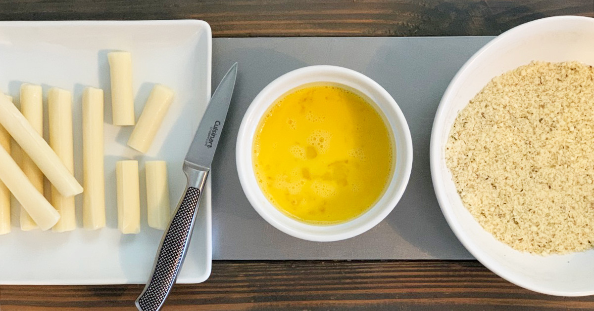 A counter set with cut string cheese, egg wash and keto "breading"