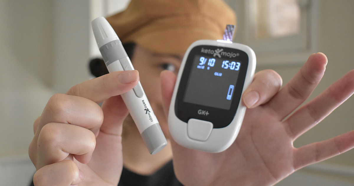 woman holding Keto Mojo monitor and lancet