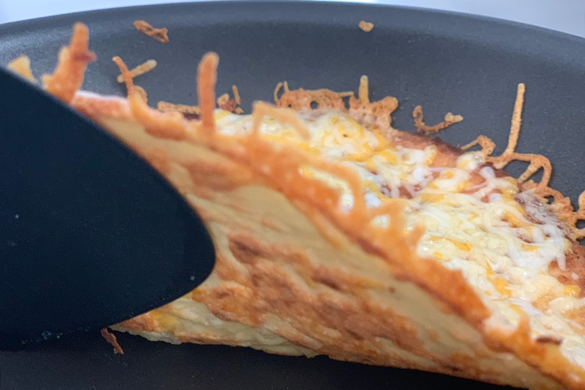 a ketodilla tortilla ready to be flipped in a pan