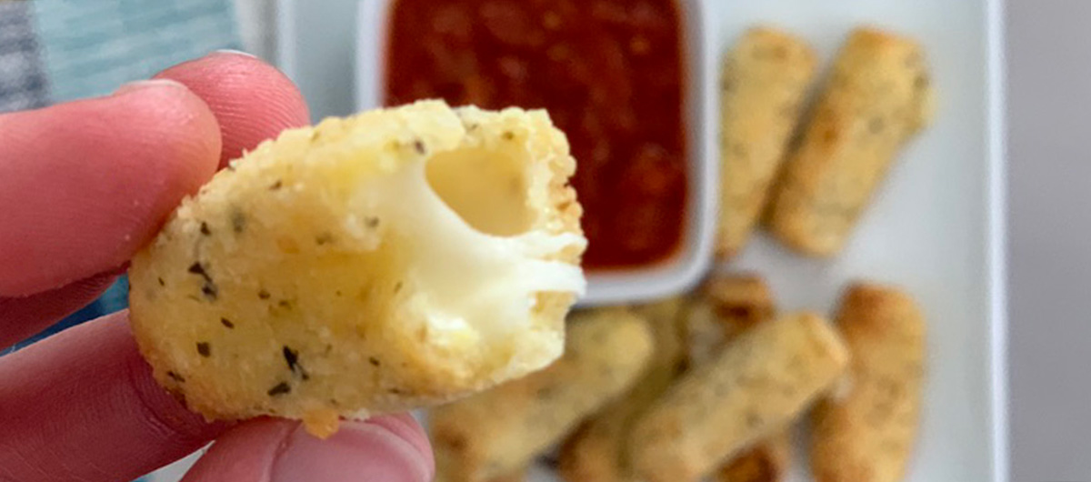 A cheesy peek inside the crispy shell of a keto fried mozzarella stick