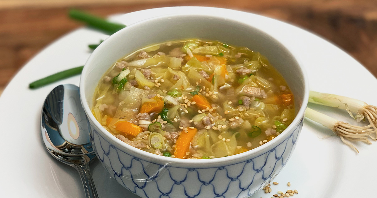 A bowl of keto Chinese pork egg roll soup garnished with green onions and toasted sesame seeds