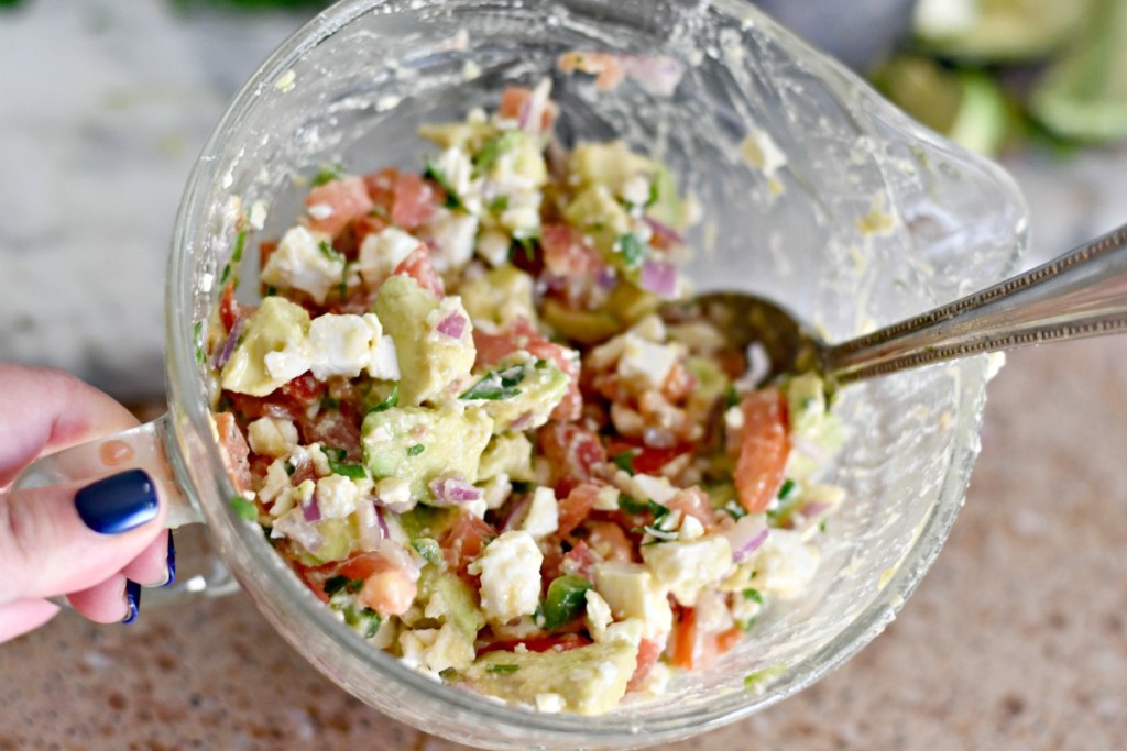 mixing avocado feta salsa in a bowl