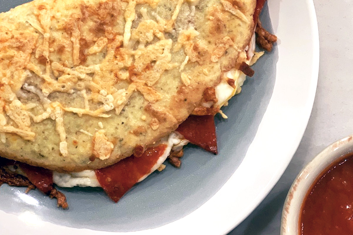 a plate with a keto pizza pocket known as a pizzadilla served with marinara sauce