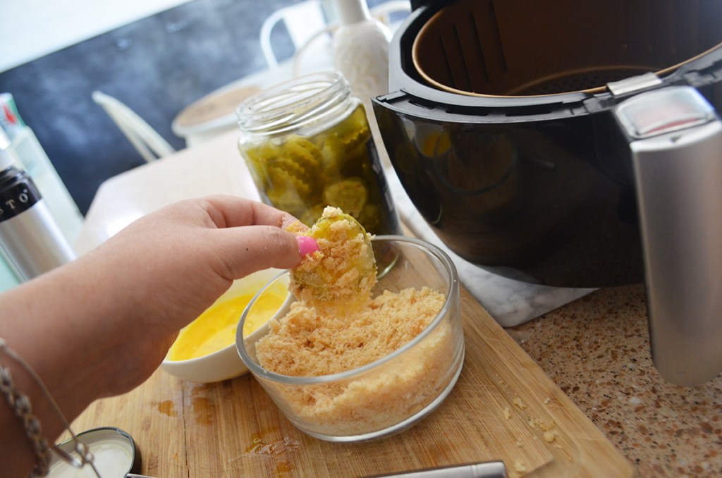 dipping pickle slice into pork rind coating