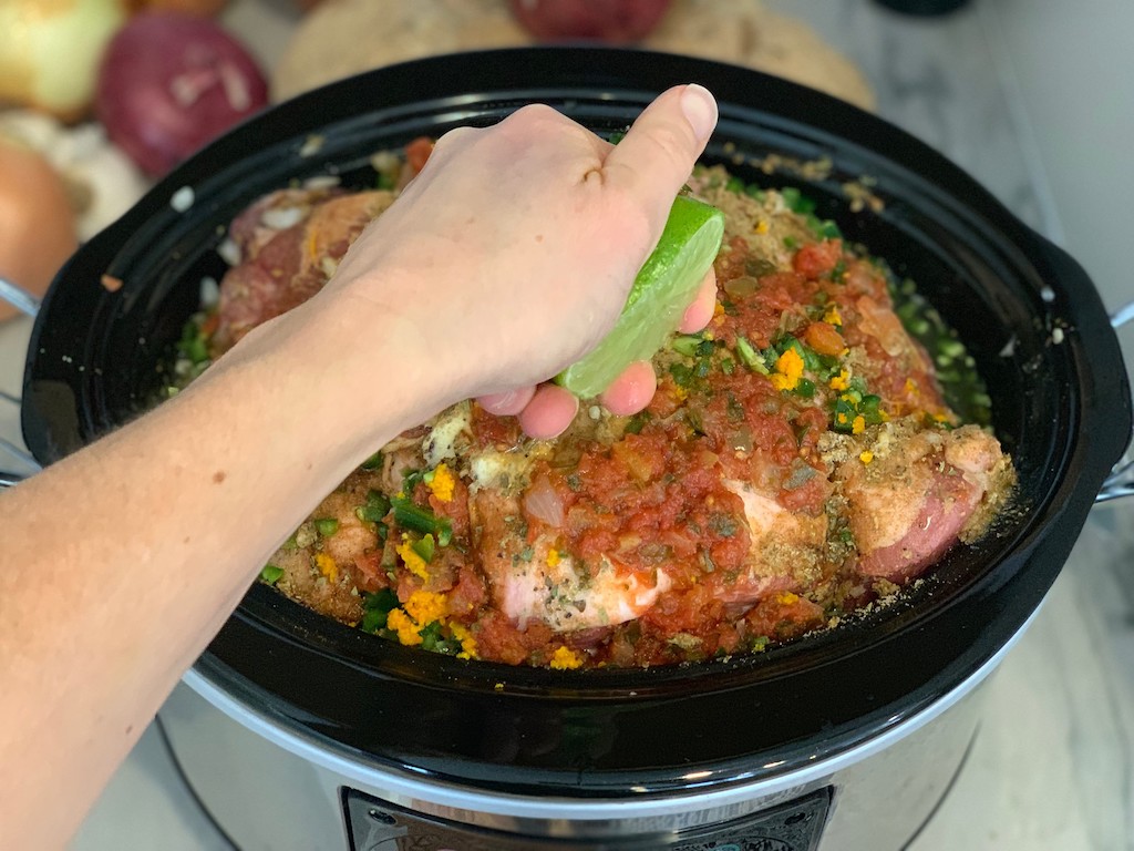 squeezing fresh lime over pork roast in the slow cooker 