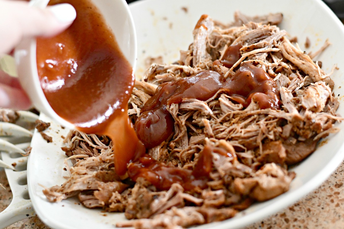 pouring sugar free bbq sauce on pulled pork