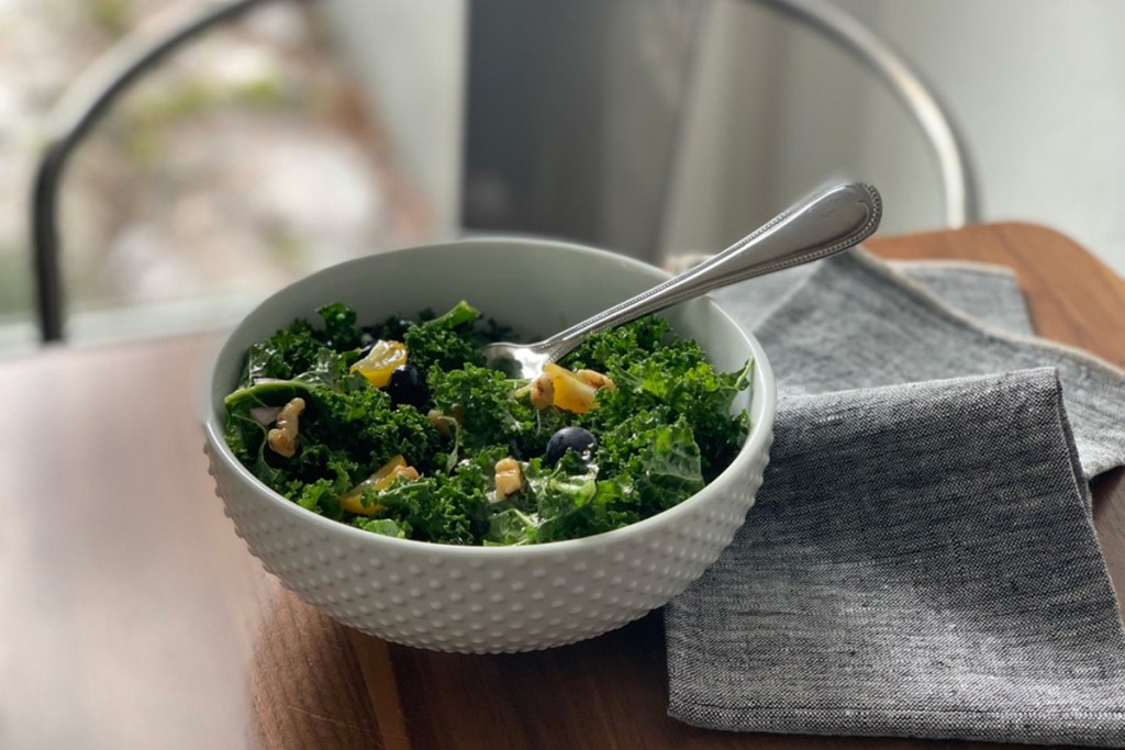 a white salad bowl with a helping of kale superfood salad