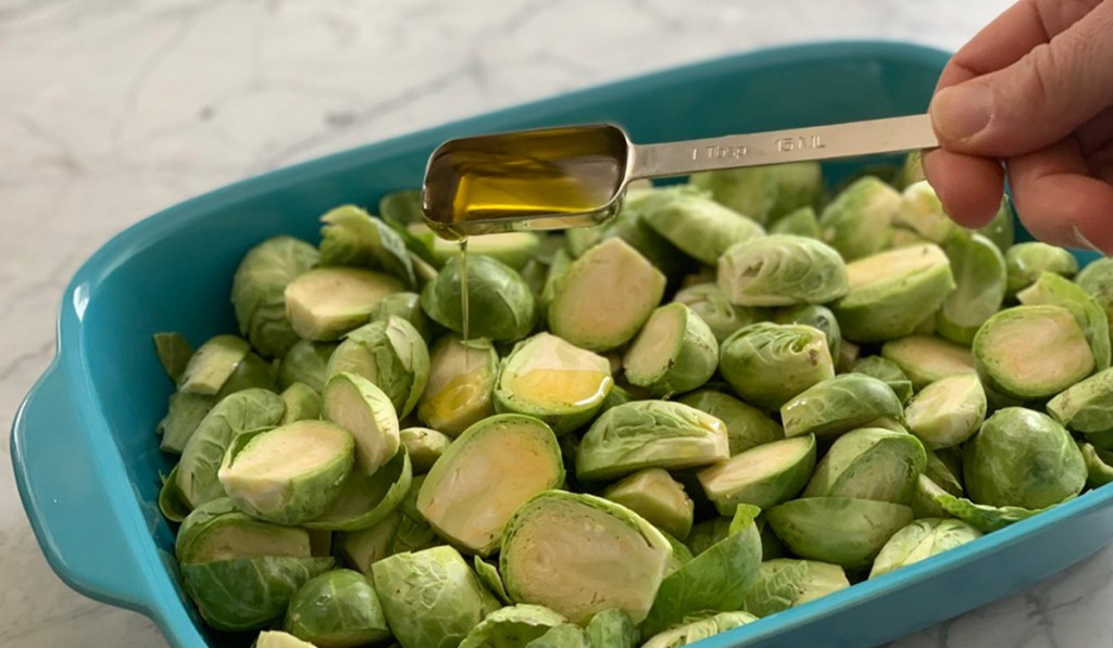 raw Brussels sprouts being drizzled with olive oil