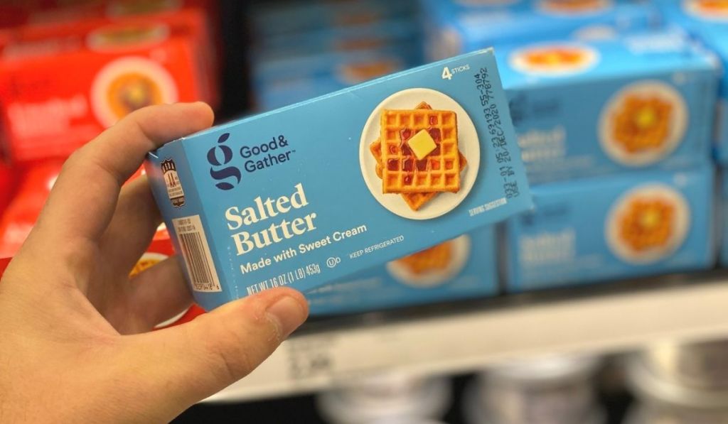 A hand holding up a box of salted butter at a store
