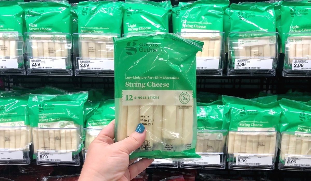 A hand holding up a bag of string cheese at a store