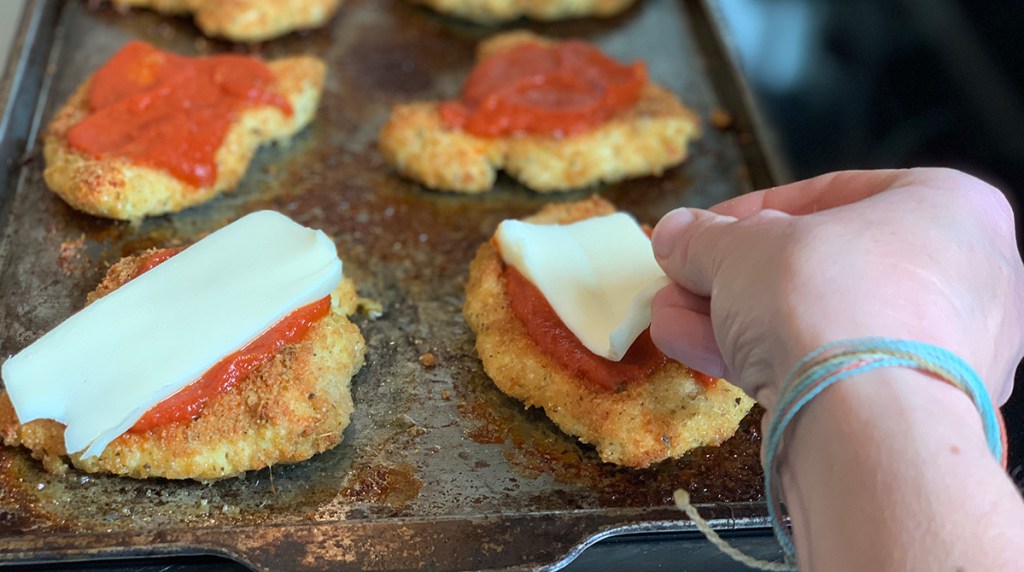 adding cheese to breaded chicken