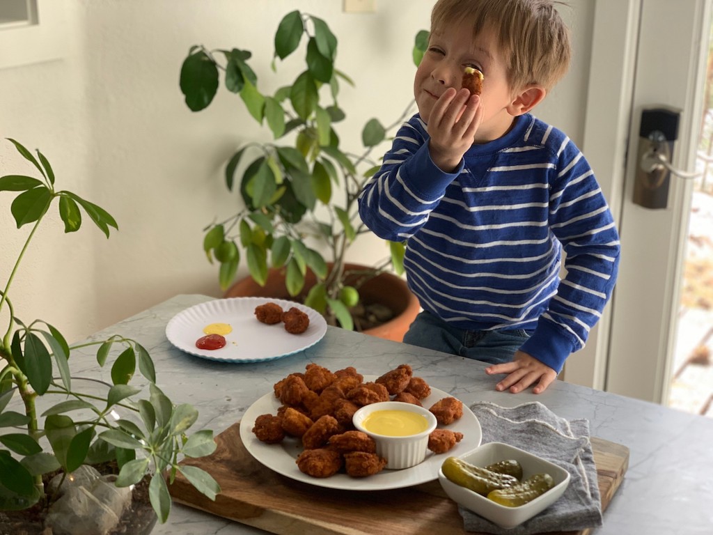 little boy holding chicken nugget with honey mustard sauce