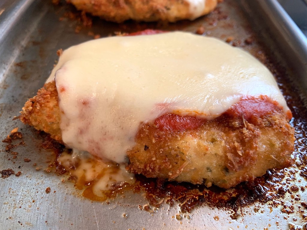 chicken parmesan with melted cheese on pan 