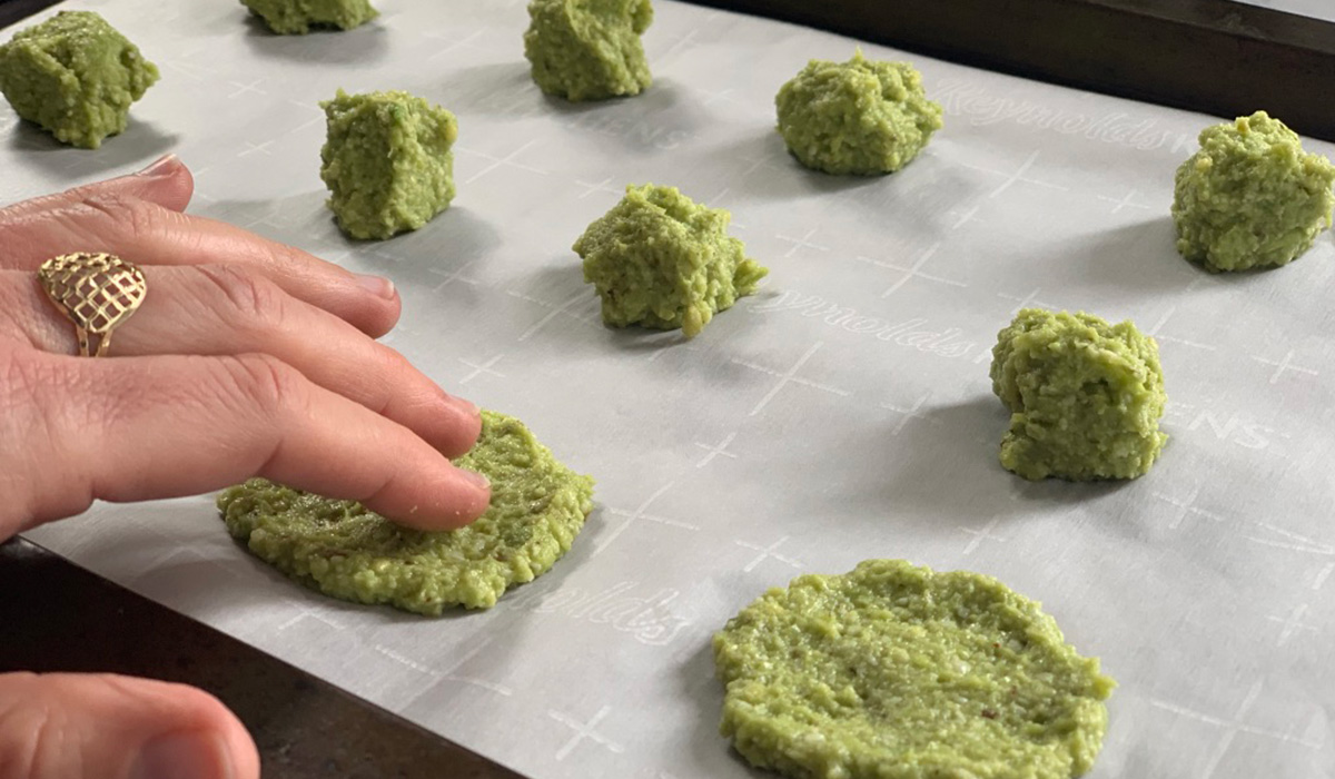 fingers pressing down avocado cheese batter into circles