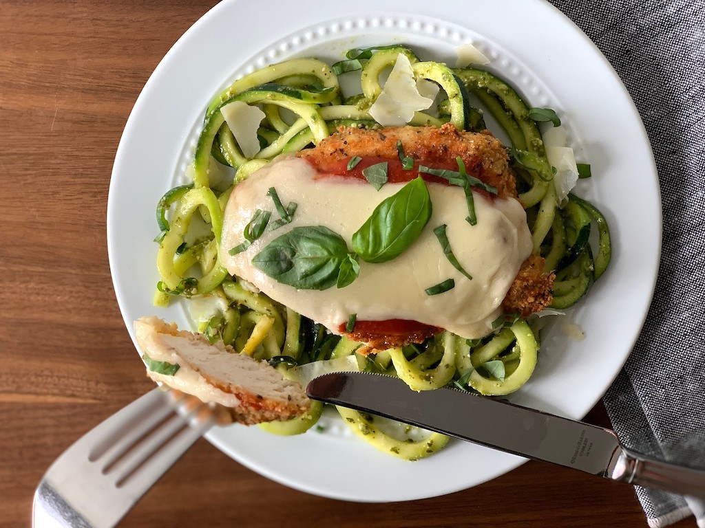 taking a bit of chicken parmesan with pesto noodles 