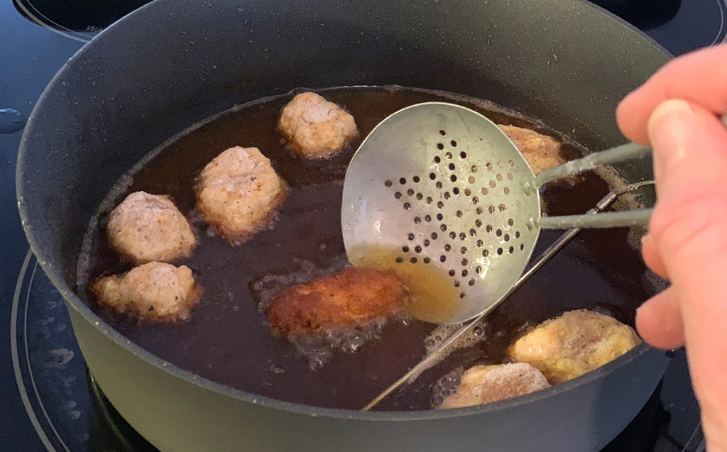 breaded chicken bites in pan of frying oil