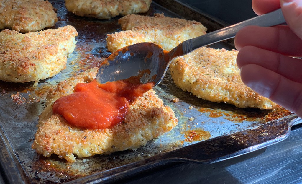 adding sauce to keto breaded chicken