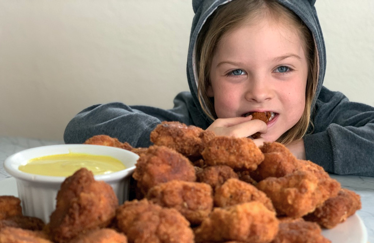 young girl eating a tasty southern fried chicken bite