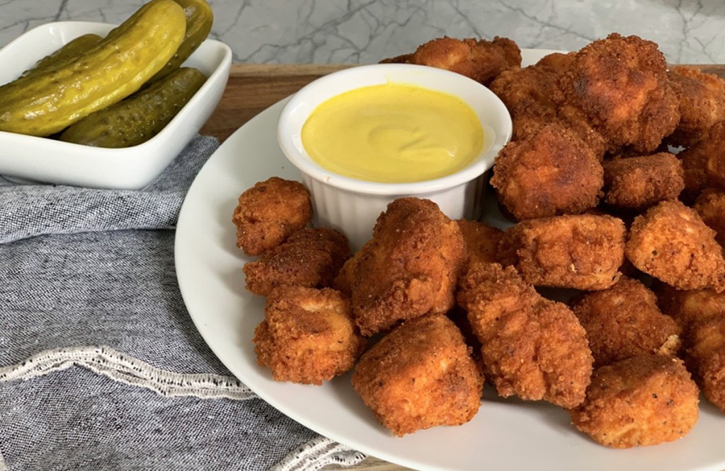 plate of chicken bites with honey mustard dipping sauce and pickles