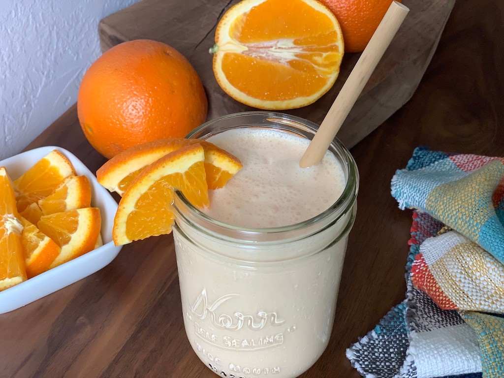 orange julius copycat drink in mason jar with fresh oranges 