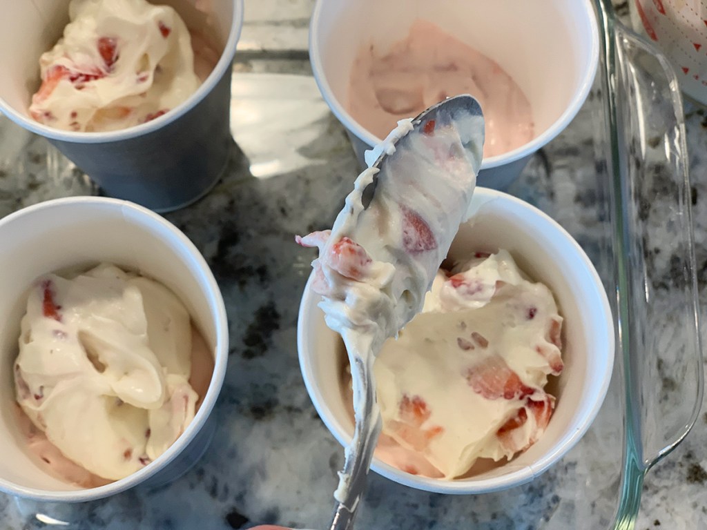 spooning in strawberry cheesecake popsicle mix into dixie cups