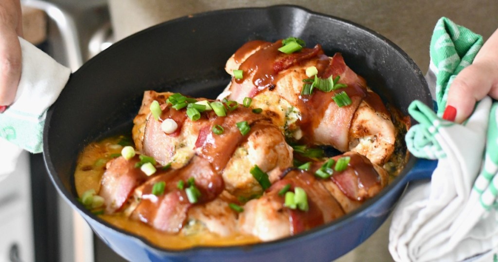 holding a skillet of bacon broccoli and cheese stuffed chicken