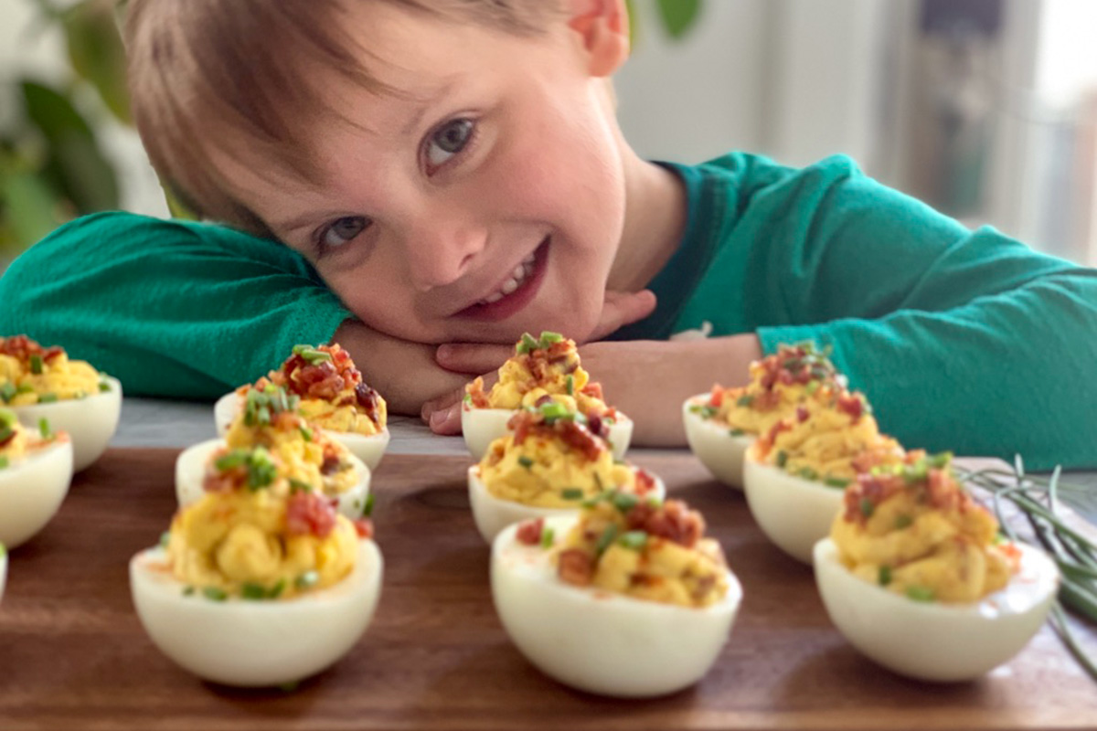 a young boy smiling over a tray of deviled eggs