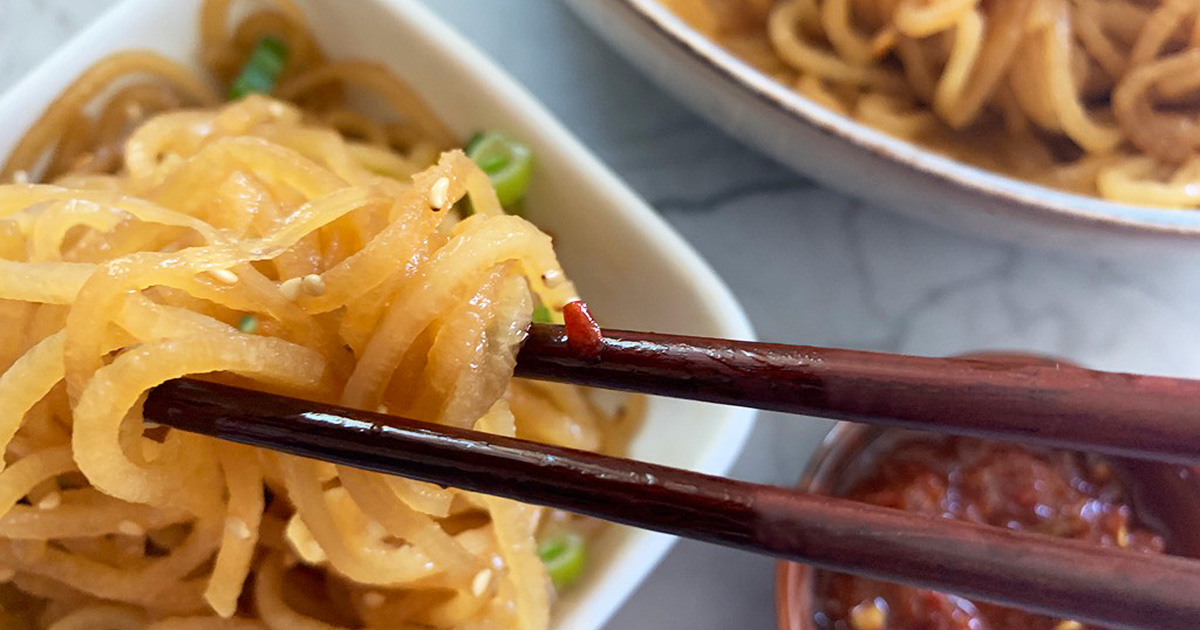 chopsticks picking up daikon radish sesame noodles