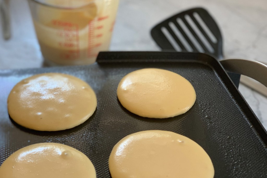 keto pancakes cooking on a hot griddle