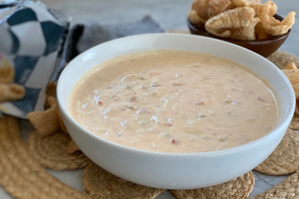 a bowl of queso served with pork rinds