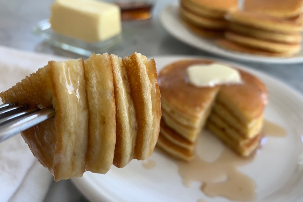 a large bite of low-carb pancakes with syrup and butter