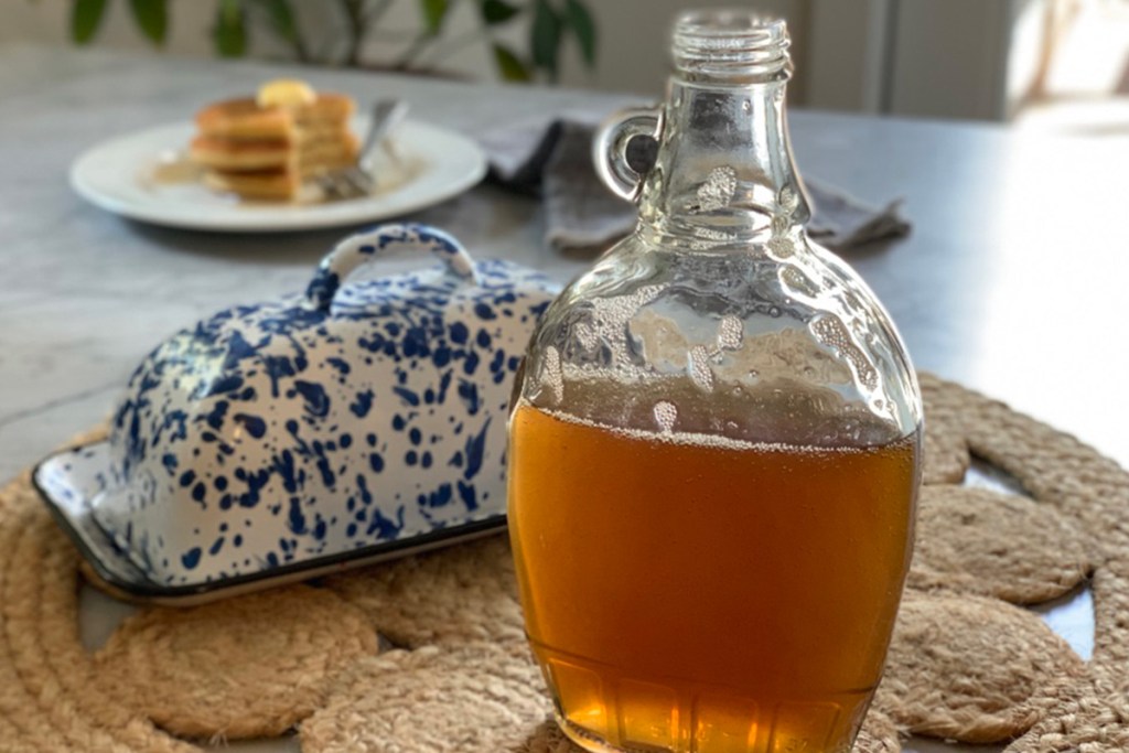 a glass bottle of keto pancake syrup on a table with a butter dish