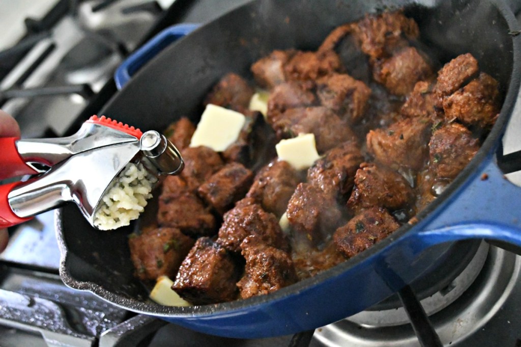 adding garlic butter to cajun steak bites