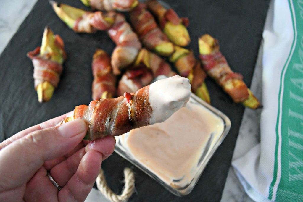 dipping a keto bacon wrapped avocado into mayo dipping sauce 