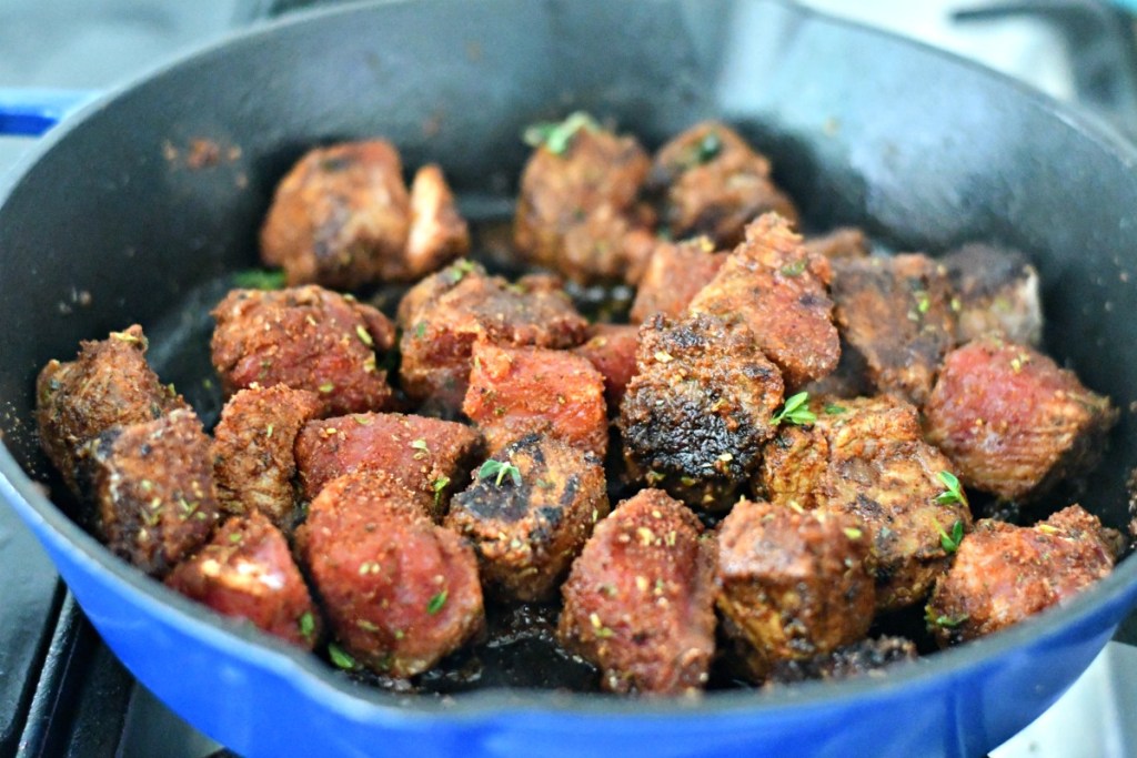 cajun seasoned steak cubes cooking in a skillet 