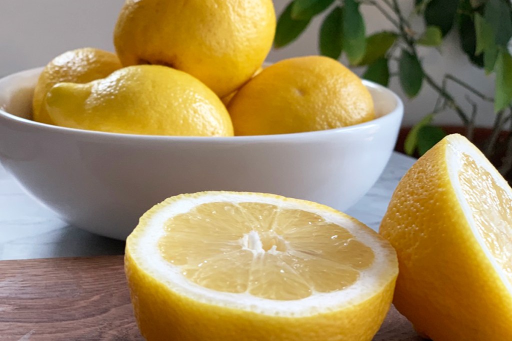 a bowl of lemons and a cutting board with a freshly sliced lemon