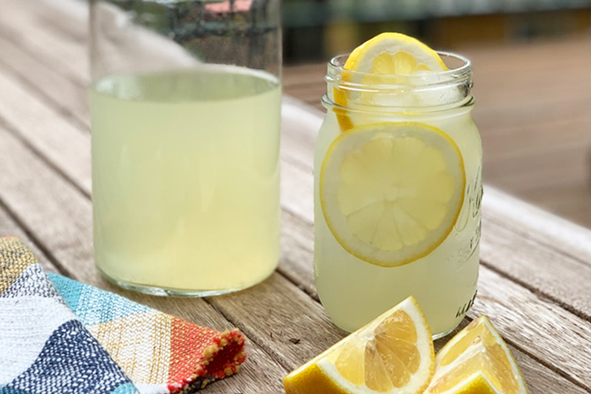 a pitcher of keto lemonade next to a glass of iced lemonade