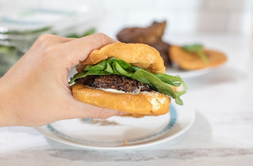 hand holding veggie burger on cloud bread with lettuce