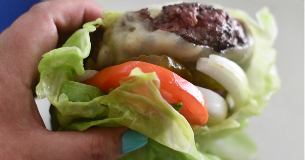 Holding keto burger wrapped in cabbage 
