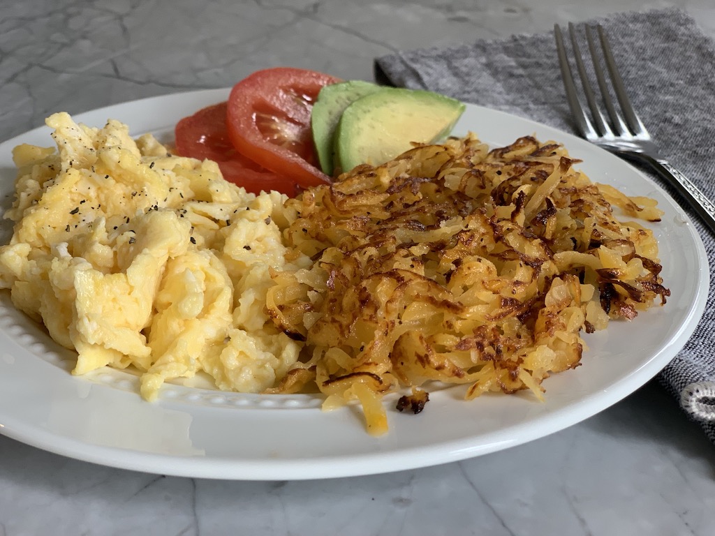 a lovely plate of breakfast that includes scrambled eggs and keto rutabaga hash browns 