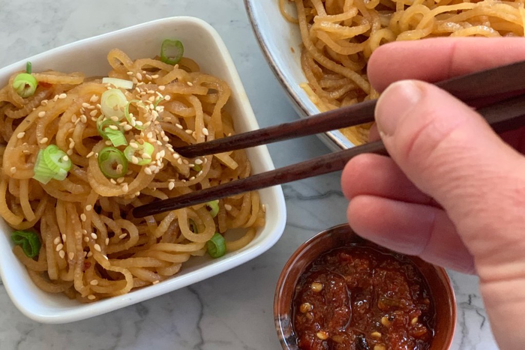 chopsticks picking up low-carb sesame noodles