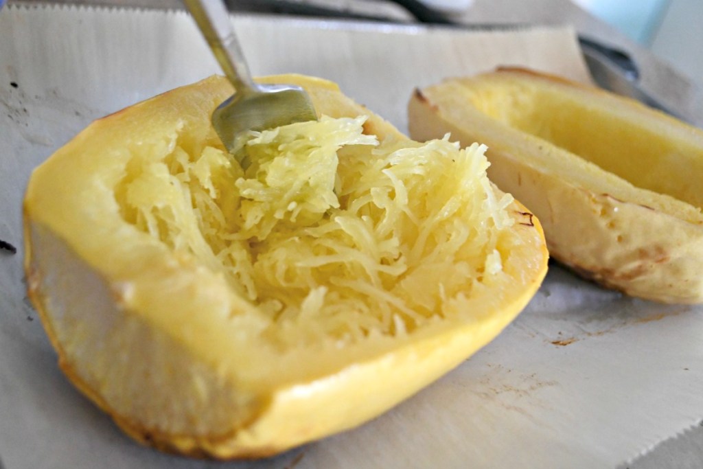 scooping baked spaghetti squash out of shell